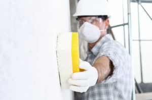 Man holding a sponge wiping a wall