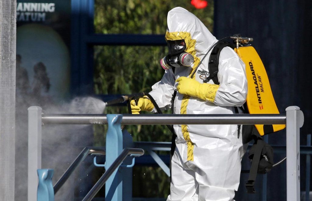 Man in hazmat suit using an Intelagard sprayer unit